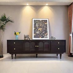 a living room with an entertainment center and potted plants on the sideboard in front of it