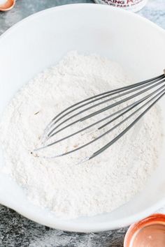 a white bowl filled with flour and whisks