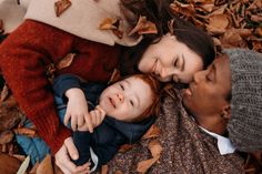 two adults and a child laying in leaves