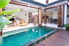 an indoor swimming pool in the middle of a house with wooden decking and sliding glass doors