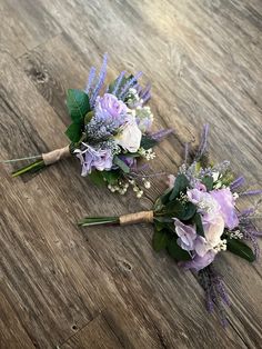 two purple and white bouquets sitting on top of a wooden floor next to each other