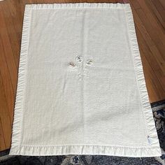 a white table cloth on the floor in front of a wooden floor with a blue rug