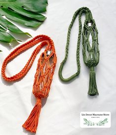 an orange and green rope with two tassels on it next to some leaves