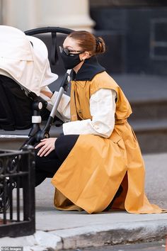 a woman wearing a face mask sitting next to a stroller