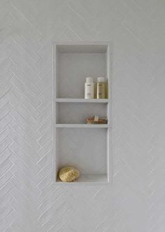 a white shelf with two shelves on it and some candles in the corner next to it