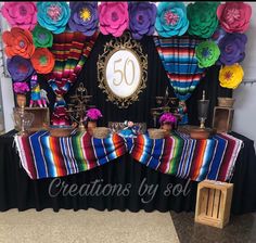 the table is decorated with colorful paper flowers and candles for an anniversary party or celebration