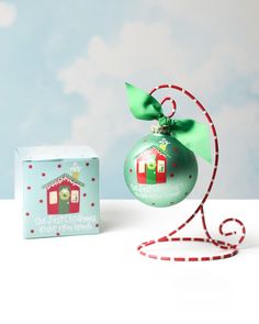 an ornament with a green bow and ribbon on it next to a box