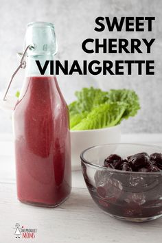 a bottle of cherry vinaigrette next to a bowl of cherries and lettuce