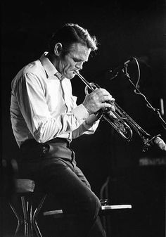 a man playing a trumpet in front of a microphone