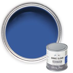 a can of blue paint next to a white wall with the words annie sloan on it