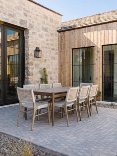 an outdoor dining table and chairs in front of a brick building with sliding glass doors