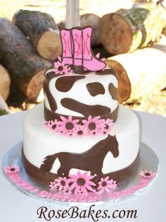 a three tiered cake decorated with pink and brown decorations on top of a table