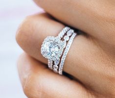 a woman's hand with a diamond ring on top of her finger and an engagement band