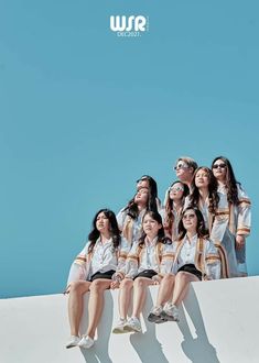 a group of young people sitting on top of a white wall next to each other