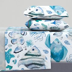 three pillows and two pillow cases on top of each other, with fish printed on them