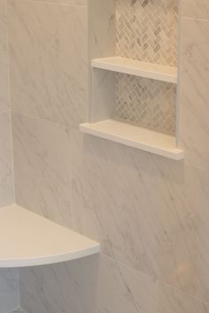 a bathroom with white marble walls and shelves