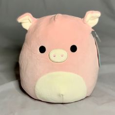 a pink pig stuffed animal sitting on top of a white tablecloth covered floor next to a gray wall