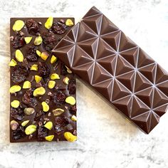 two pieces of chocolate with nuts and dried cherries on top, sitting next to each other