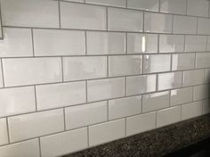 a white tiled wall in a kitchen with granite counter tops