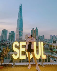 a woman standing on top of a roof talking on a cell phone in front of a cityscape