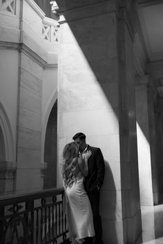 a man and woman standing next to each other in front of a building with columns