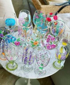 a table topped with lots of wine glasses filled with colorful flowers and plants on top of it