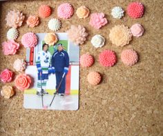 a cork board with some pictures and flowers on it, including two men in skis