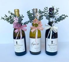 three bottles of wine with flowers in them