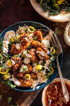 a bowl filled with chicken and vegetables next to two bowls of sauce on the table