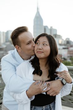 a man and woman embracing each other in front of a cityscape