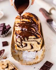 someone drizzling chocolate on top of a cake