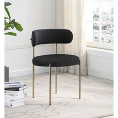 a black chair sitting on top of a white rug next to a book shelf and window