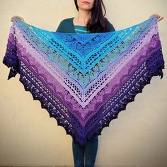 a woman holding up a purple and blue shawl