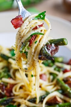 a fork full of pasta with asparagus and bacon