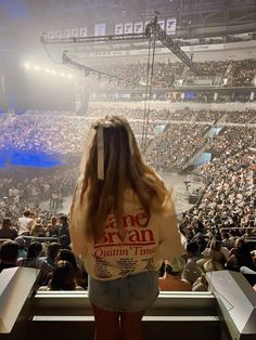 a woman standing in front of an audience at a concert looking out into the stands