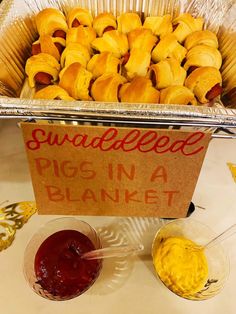 there are some food items on the table and one has a sign that says swaddled pigs in a blanket