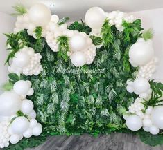 an arrangement of white balloons and greenery