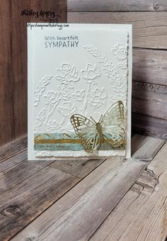 a card with a butterfly on it and the words sympathy written in gold foil, sitting on