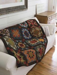 a white couch with a quilt on it