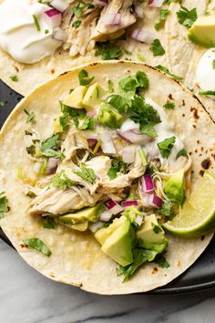 two chicken tacos with avocado, cilantro and sour cream sauce