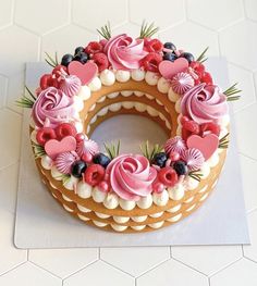 a cake decorated with pink and white icing on top of a counter next to a tile floor