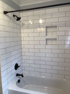 a bathroom with white subway tile and black faucet shower head in the corner