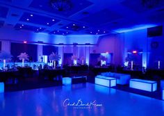 an empty dance floor with blue lights and couches in the center is lit up