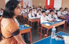 a woman standing in front of a classroom full of students sitting at desks and using laptop computers