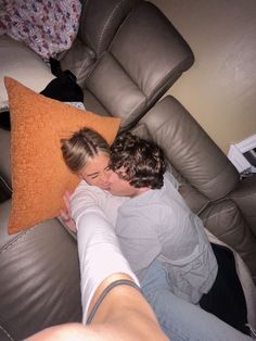 a man and woman cuddle on the back of a couch