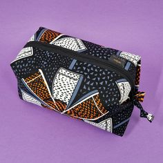 a black and white bag with an orange design on the front, sitting on a purple background