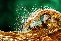 an open can of beer splashing into the water