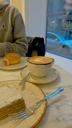 a person sitting at a table with two plates of food and a cup of coffee