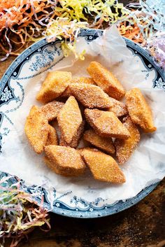 a plate full of sugared donuts on a table with sprinkles