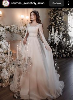 a woman in a wedding dress standing next to a chandelier with candles on it